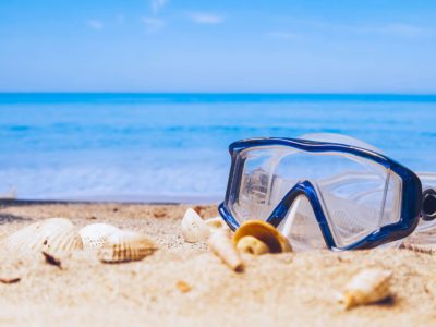 Snorkel mask on a beach with sea shells