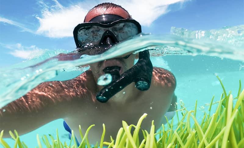 Snorkeling Tip: Prepare your gear for the water like this man preparing his snorkel mask